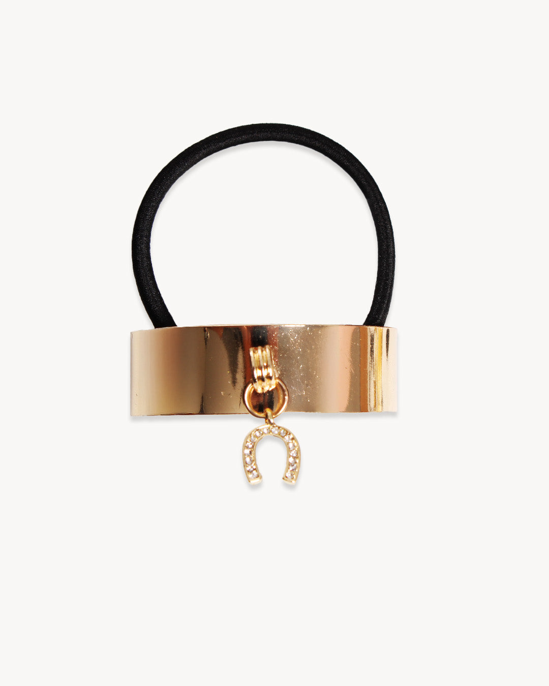 Gold hair tie with a horse shoe charm on a white background