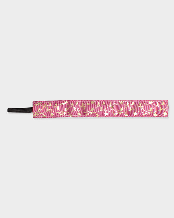Pink headband with gold vine pattern on a light gray background