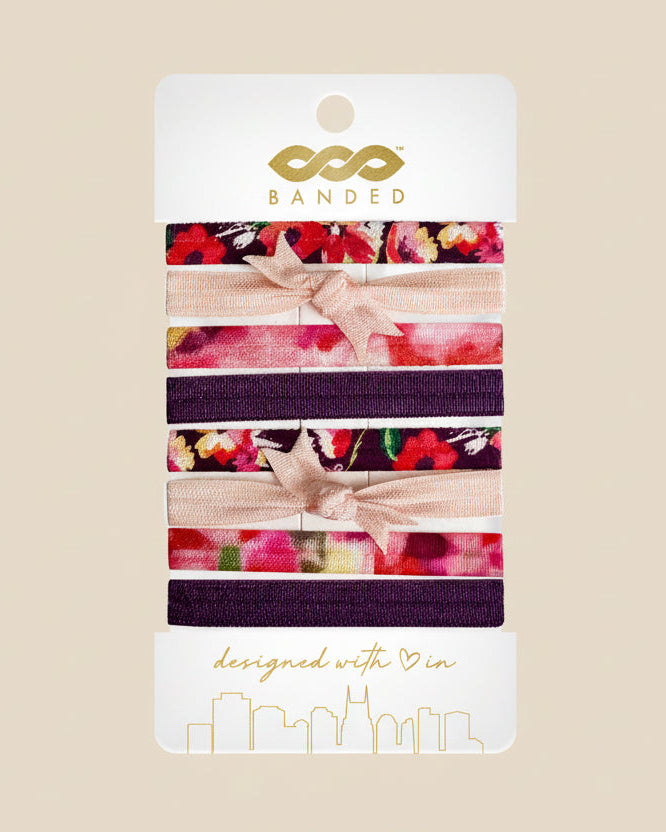 Pack of hair ties with floral and bow designs on a 'Banded' branded card.
